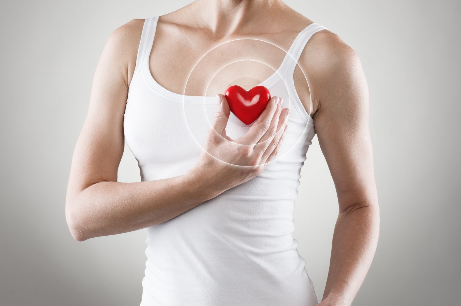 Mujer sosteniendo un corazón de jugete arriba de su corazón