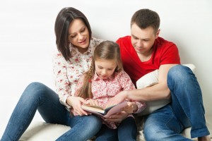 Padre y madre leyendo con una niña