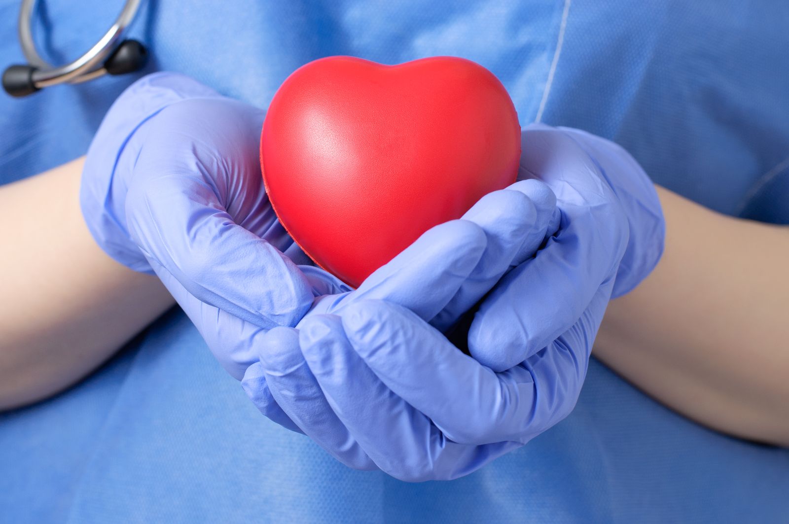 Doctor vestido de azul sosteniendo un corazón rojo de juguete