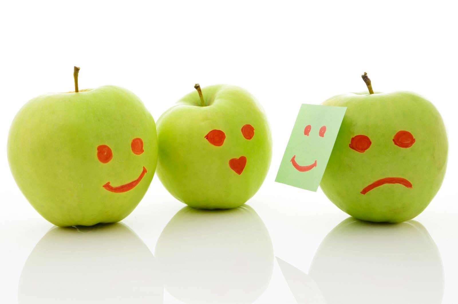 Tres manzanas con rostro una escondiendo tristeza