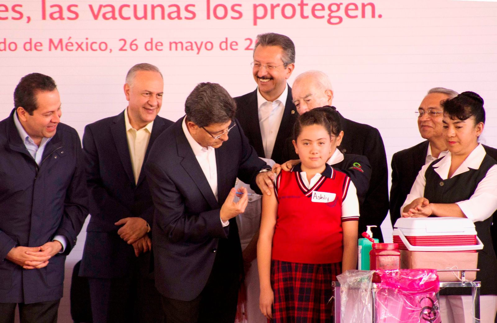 Funcionarios observando a Pablo Kuri aplicando una vavuna a una niña