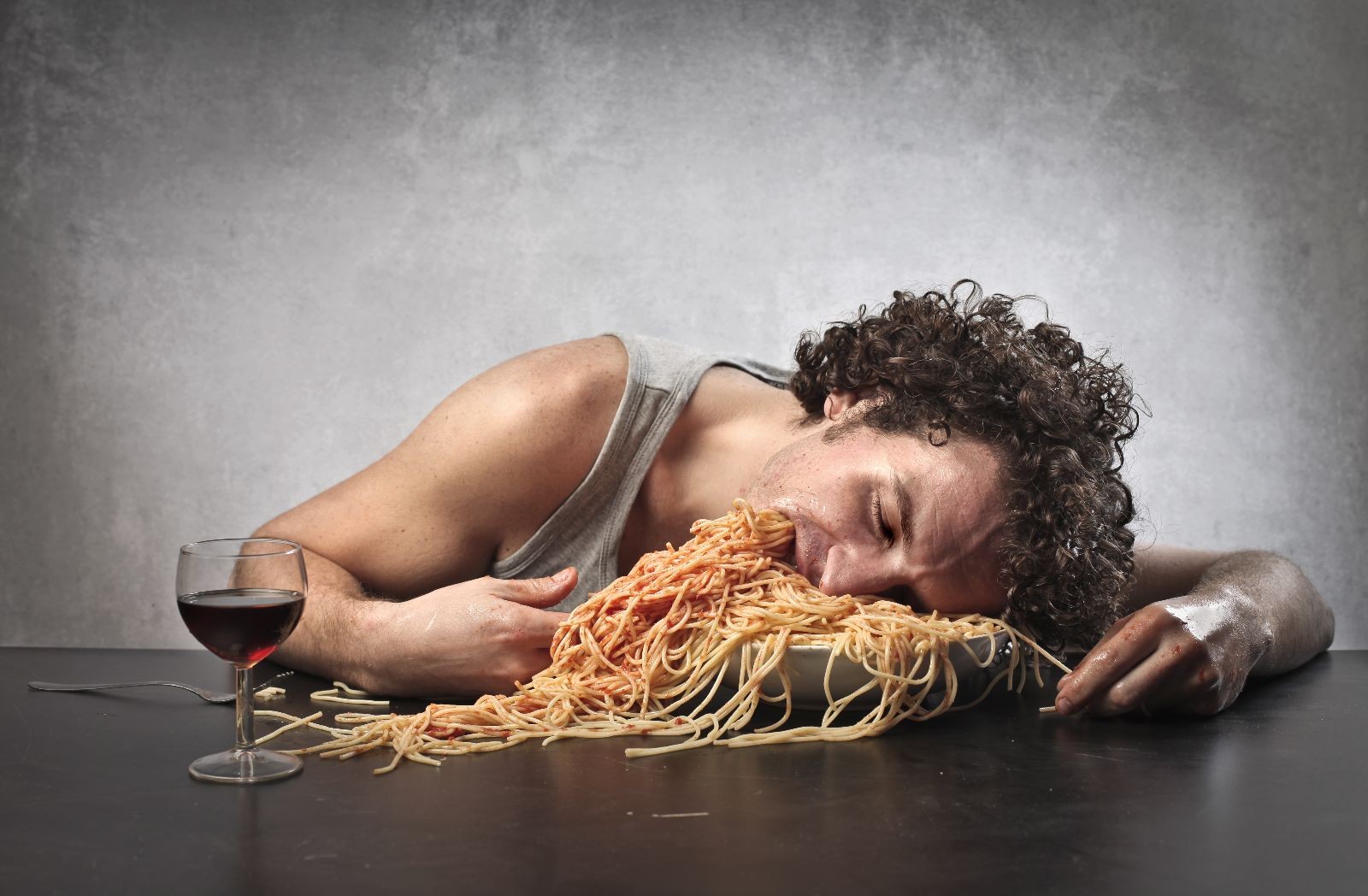 Hombre somnoliento comiendo una cantidad excesiva de espaguetti