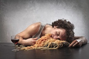 Hombre somnoliento comiendo una cantidad excesiva de espaguetti