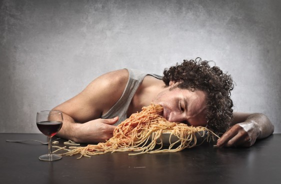 Hombre somnoliento comiendo una cantidad excesiva de espaguetti