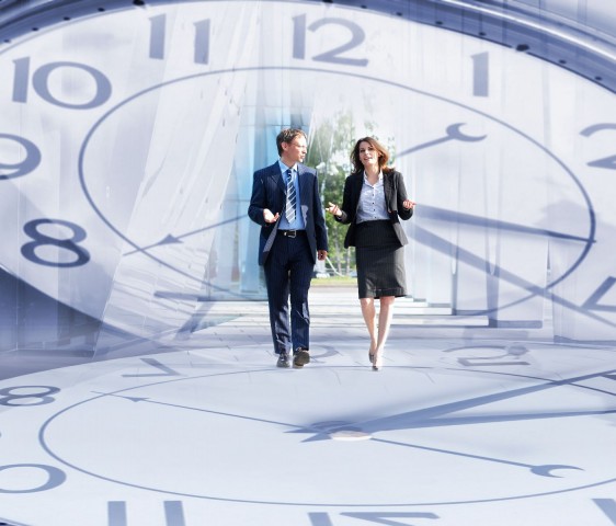 Imagen de un reloj en el centro una imagen de dos ejecutivos caminando