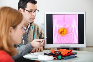 Médico muestra a una mujer en una la pantalla de computadora una ilustración del sistema gastrico