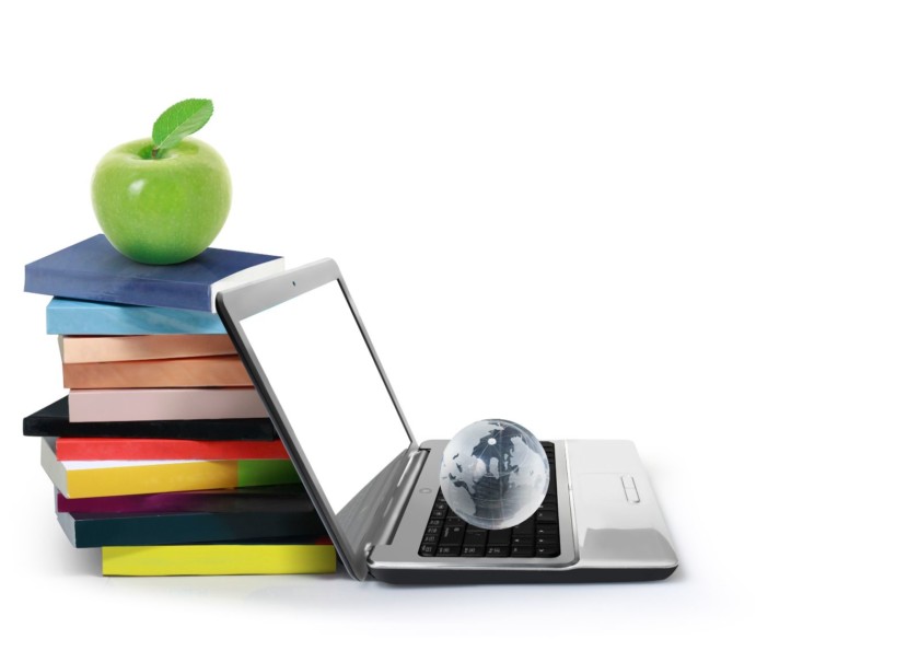 computadora con libros y una manzana