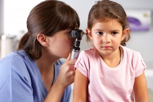 Doctora examina las orejas del una niña en el consultorio médico