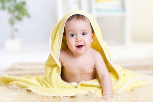 Bebé sonriendo en una toalla de baño amarilla
