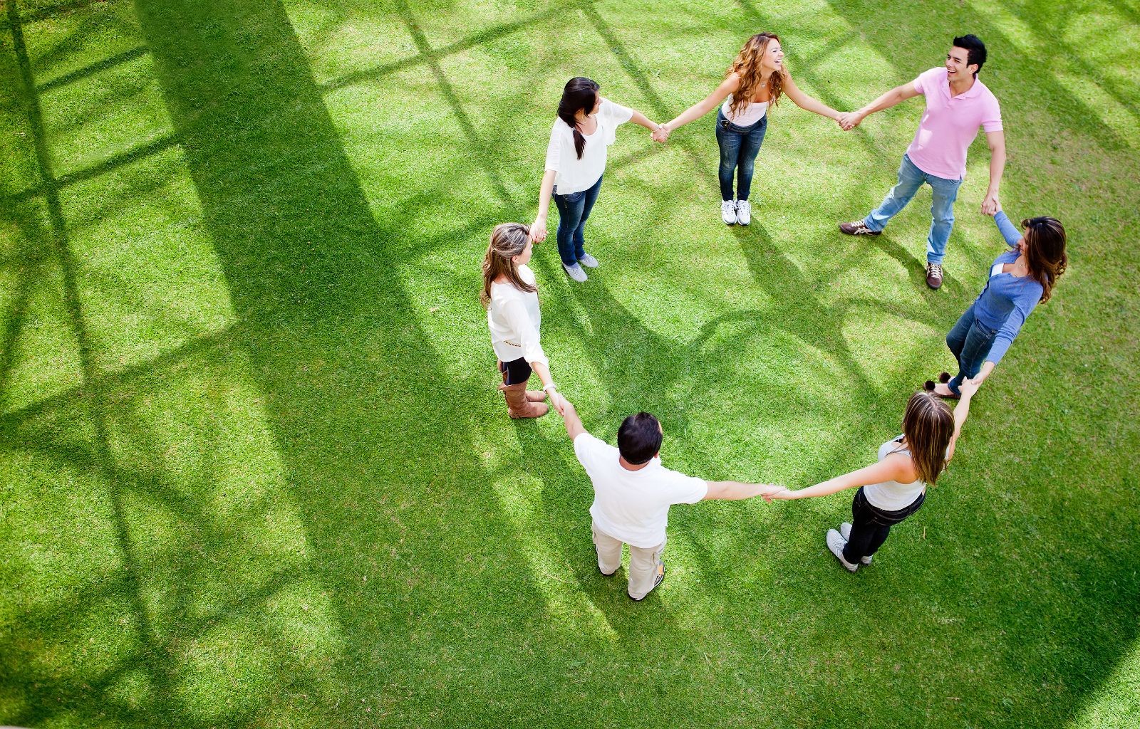 Jóvenes agarrados de las manos formando un circulo en un parque