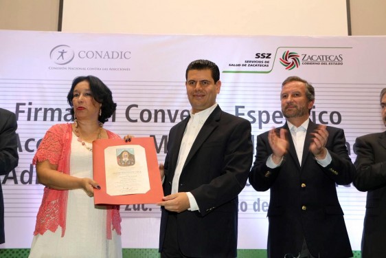 En representación del doctor Manuel Mondragón, la doctora Nora Frías recibió el reconocimiento que el gobernador  Miguel Alonso Reyes entregó al titular de CONADIC, al nombrarlo Huésped de Honor.