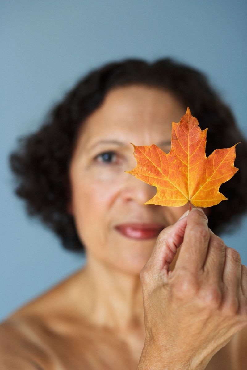 Mujer de más de cincuenta años con una hoja de otoño