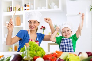 Madre e hijos sonriendo y cocinando con verduras