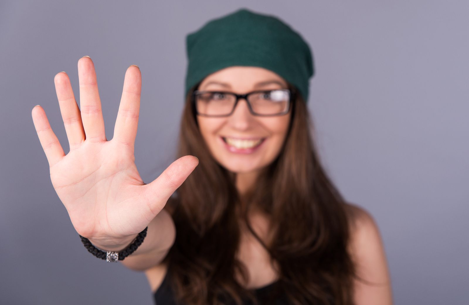 Mujer sondiendo haciendo un gesto de cinco con la mano en alto