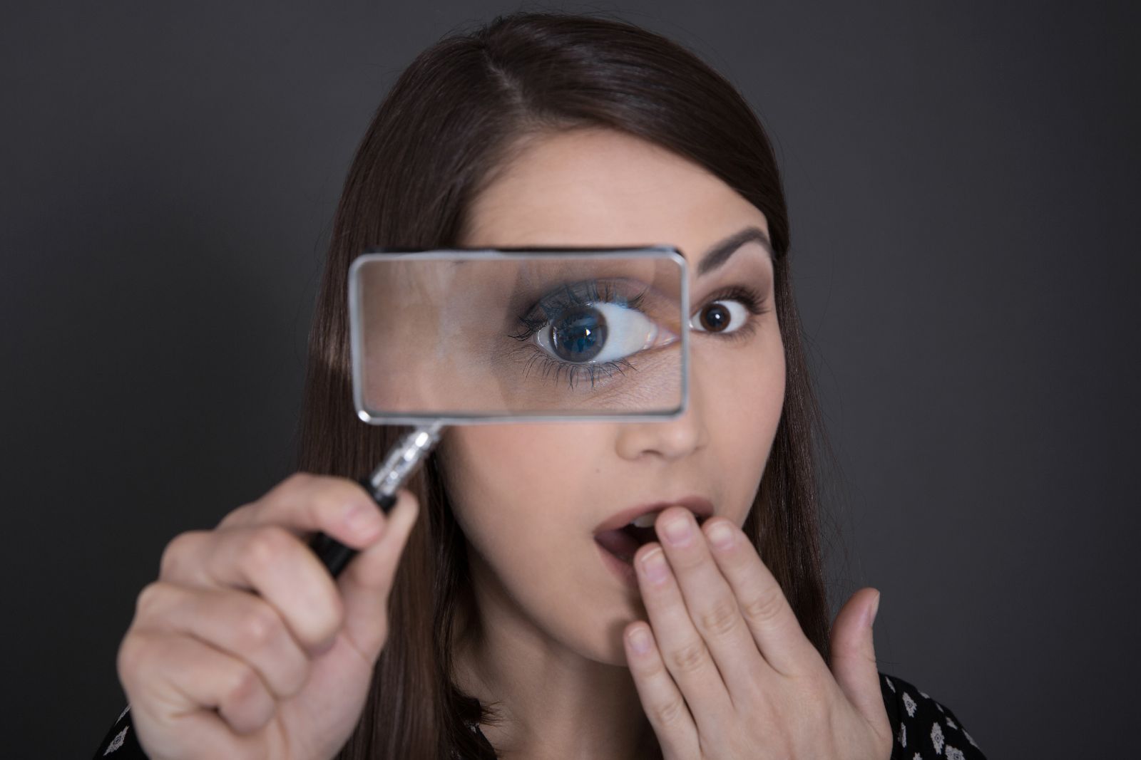 mujer sosteniendo lupa en su rostro