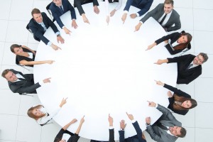 grupo de ejecutivos apuntando al centro de una mesa