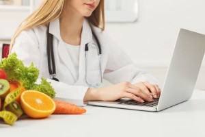 Nutrióloga con una computadora al lado de frutas
