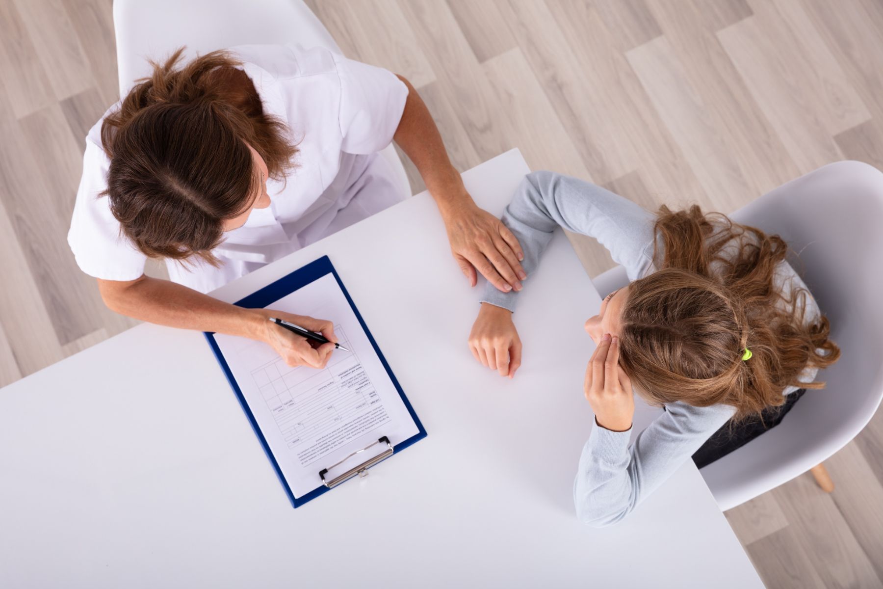 Doctora con portapapeles mirando deprimido chica paciente en clínica