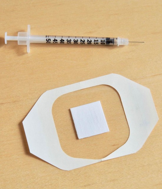 El nuevo parche se muestra debajo de una vacuna tradicional contra la gripe basada en agujas