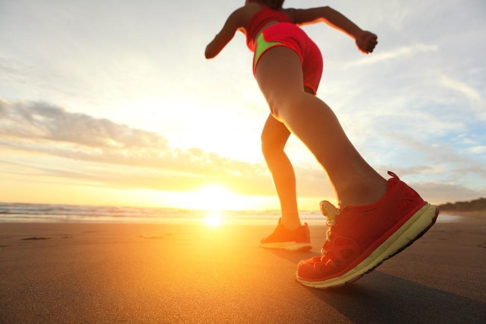 mujer corriendo hacia la puesta de sol