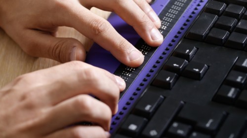 Persona ciega usando la computadora con pantalla de computadora braille