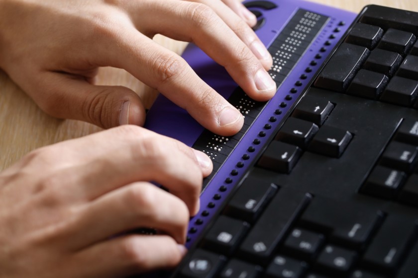 Persona ciega usando la computadora con pantalla de computadora braille