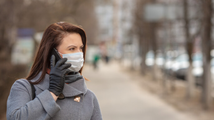 Mujer que lleva máscara médica protectora una calle vacía, al aire libre. Mujer que tiene un teléfono. Concepto de autoasistencia