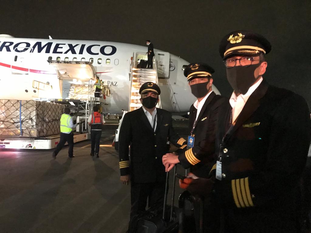 Pilotos con avión de aeromexico al fondo y descargando embalaje