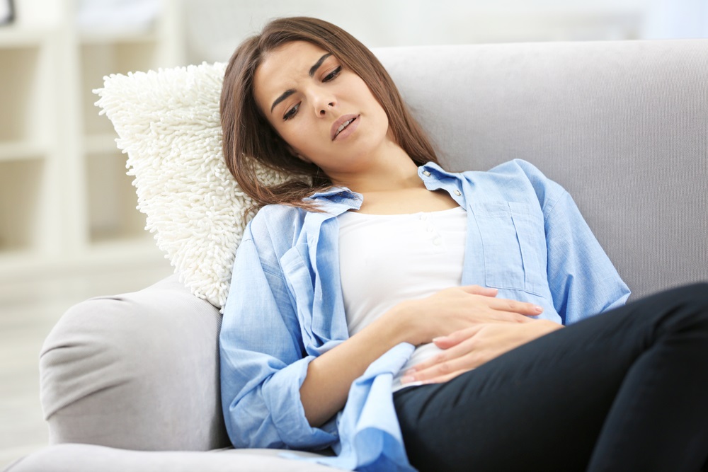 Mujer con dolor abdominal recostada en sofá