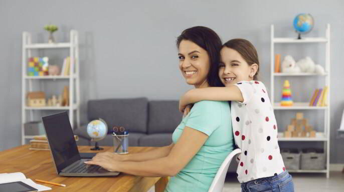 Hija abrazando a su mamá mientras trabaja en línea