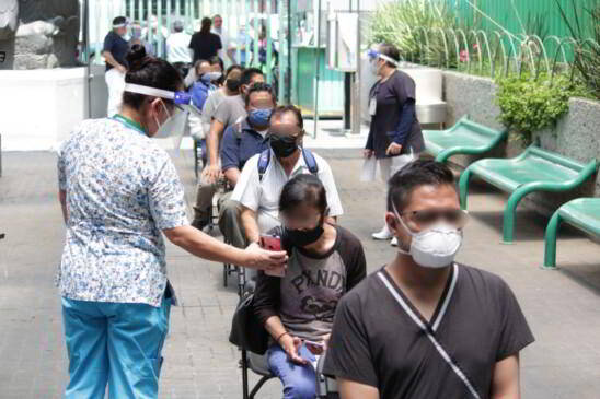 Pacientes en una fila con una especialista mostrando un dispositivo móvil