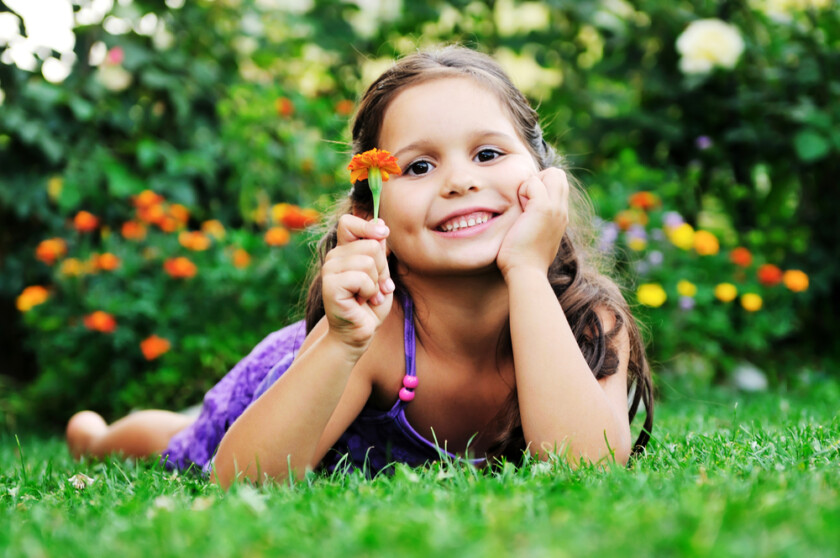 niña sonriente con flor en la mano