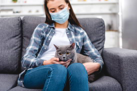 mujer joven con cubrebocas y gato