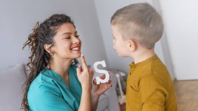 Logopeda enseñando a niño a decir letra S