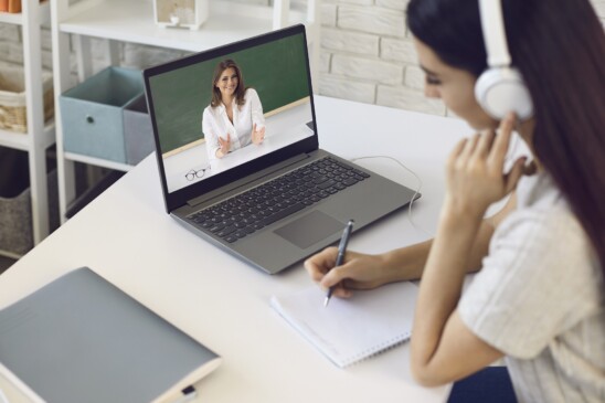 Profesor en línea. Estudiante con auriculares escucha video