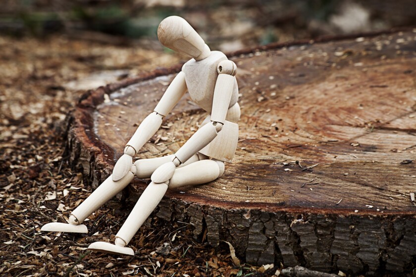 Muñeco de madera sentado en un tronco