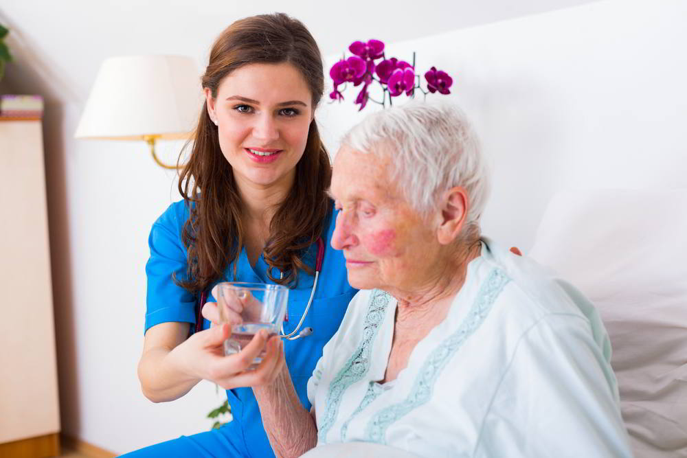 Enfermera cuidadora ayudando a anciana enferma