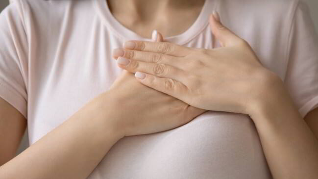 mujer manteniendo mano en el pecho con señal de esperanza