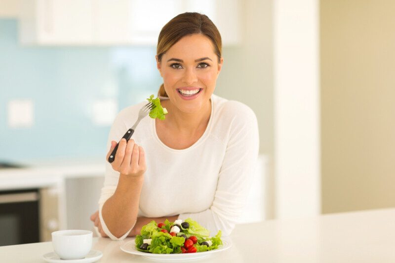 Mujer comiendo ensalada verde