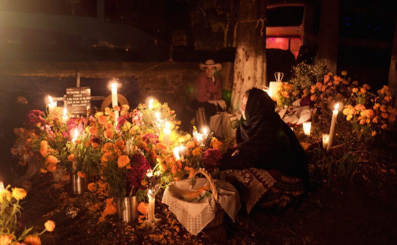 Mujer con ofrenda del día de muertos en un panteón