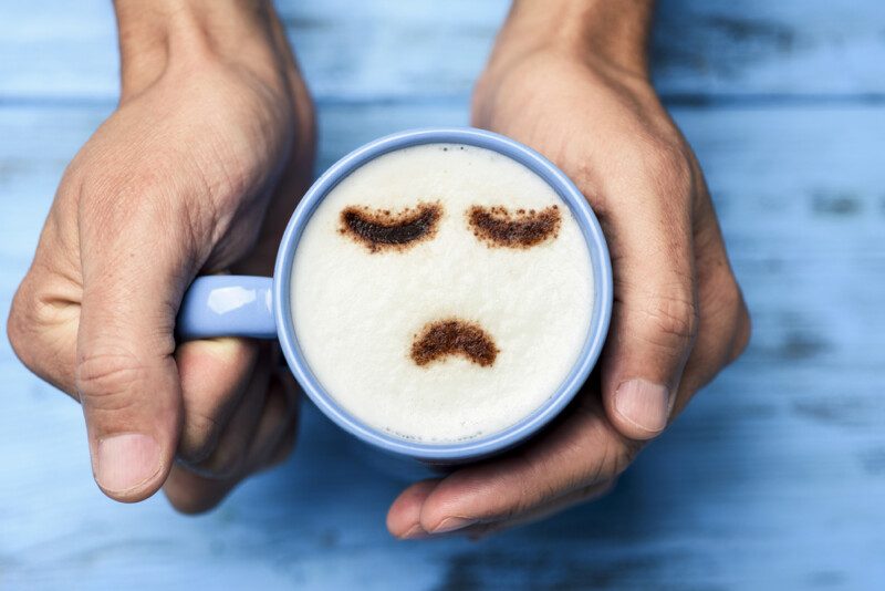 Hombre con una taza de capuchino con una cara triste