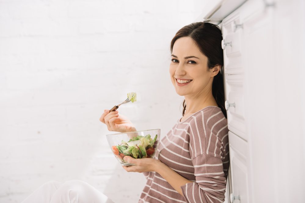 Feliz joven mujer mirando a la cámara mientras está sentada