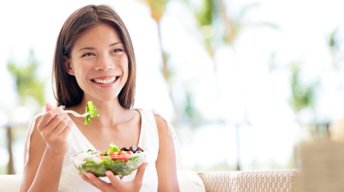 Estilo de vida saludable mujer comiendo ensalada sonriendo feliz