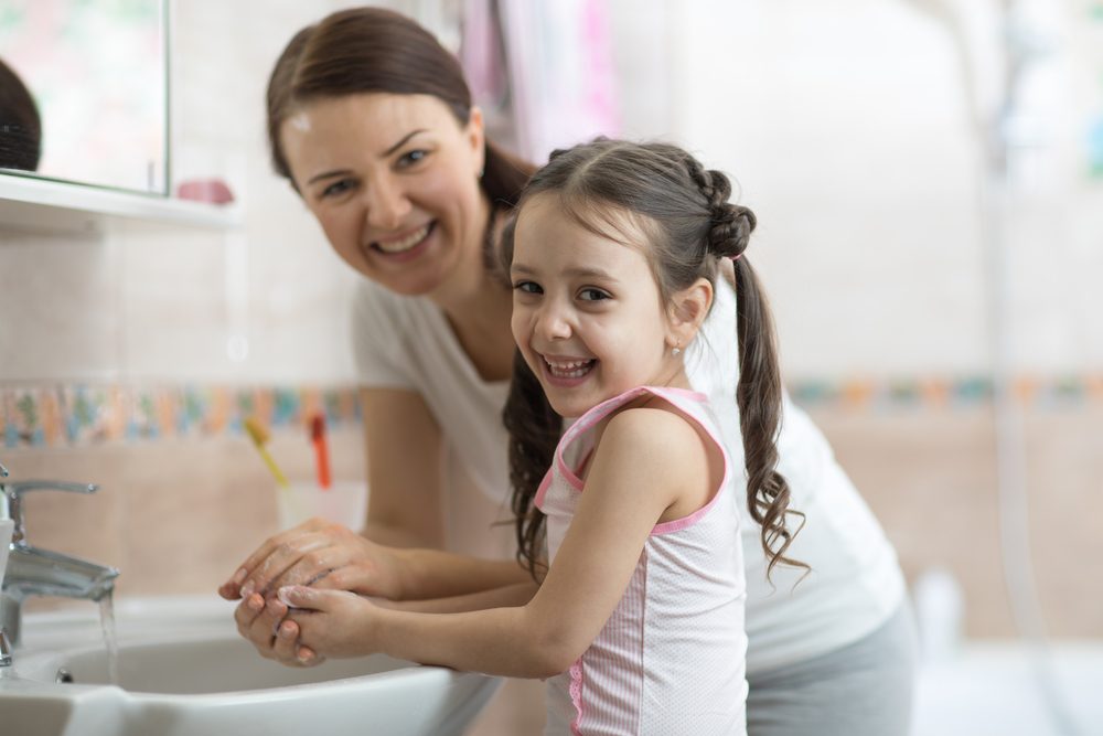 Niña con mamá lavándose las manos en el baño