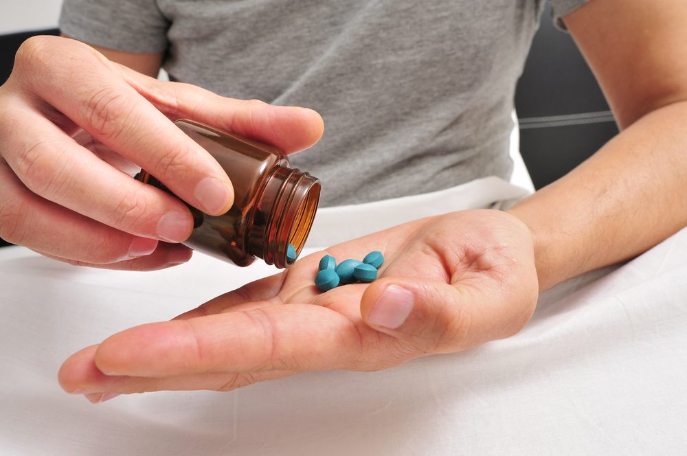 Hombre en la cama a punto de tomar algunas pastillas azules