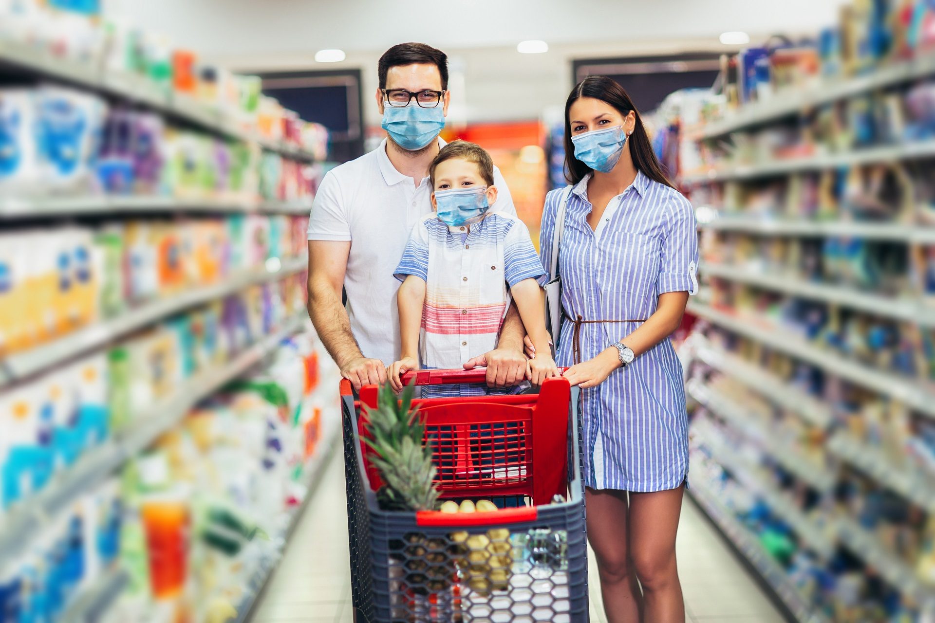 Familia feliz con mascarillas en el súper mercado