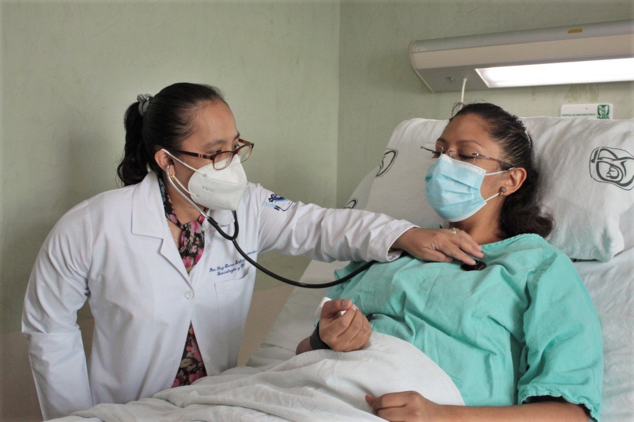 Doctora con estetoscopio atendiendo paciente en cama