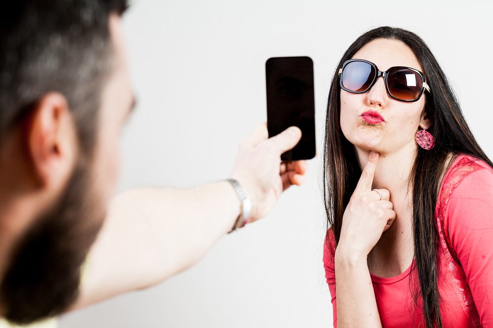 Pareja emocionada tomando fotografías móviles y selfies