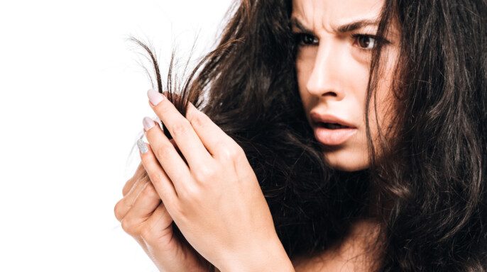 Mujer estresada mirando el cabello seco dañado