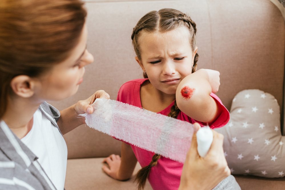 Madre preocupada herida vendaje alrededor del codo de la hija